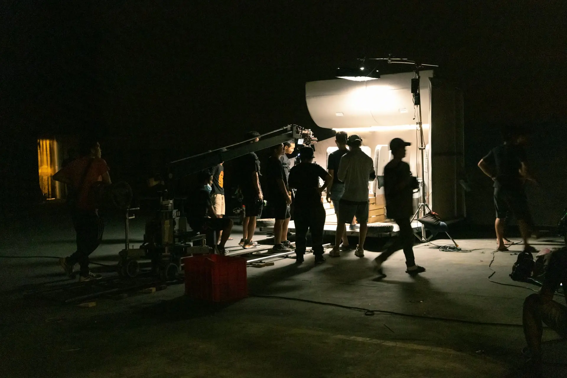Film crew shaping a scene with a camera crane and studio lighting